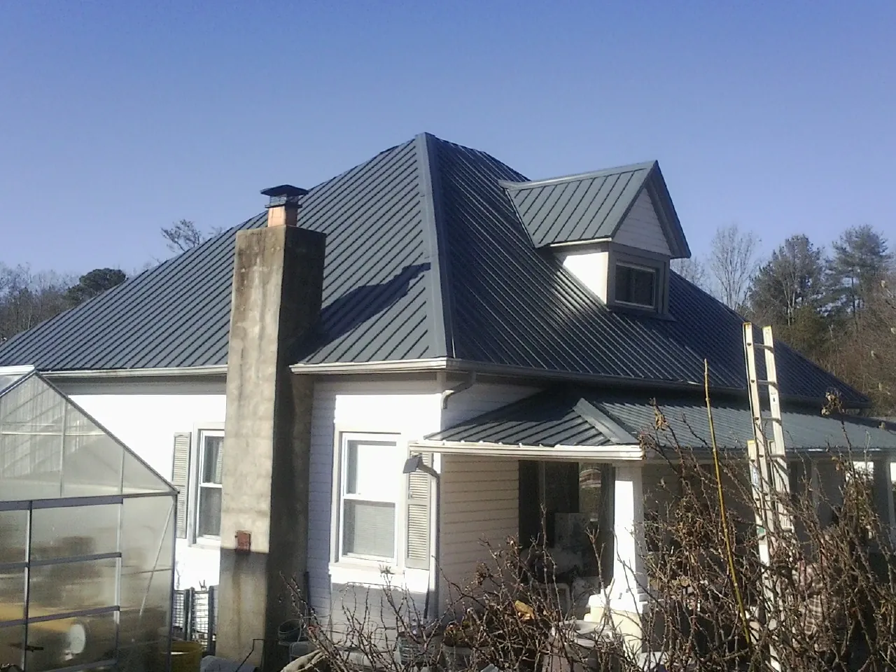 Dark blue standing seam metal roof on a white farmhouse with dormer — Slate & Tile Roof Repair by Roofing Brothers in Wallis