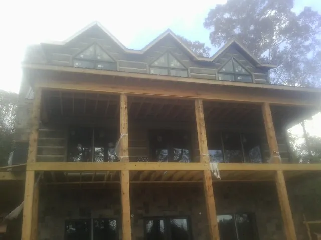 Dormers and porch framing on a large log home under construction — Roof Coating work by our crew in Wallis