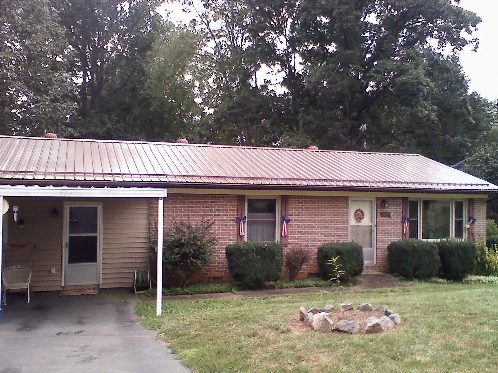 Bronze metal roof and carport on a brick ranch home — Roof Repair work by our crew in Wallis
